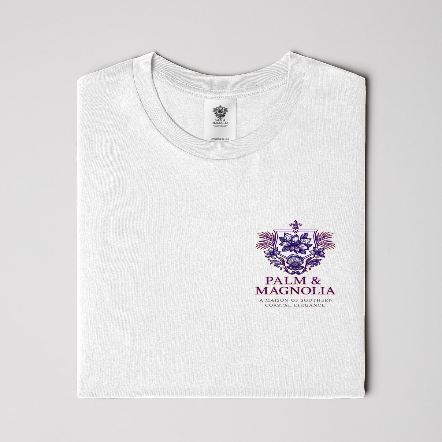 White ring-spun cotton tee folded, displaying purple Palm & Magnolia poodle emblem.