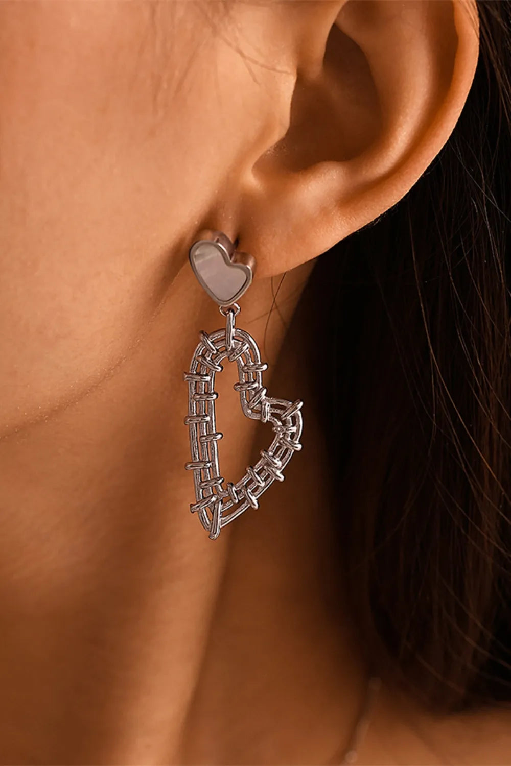 Silver heart-shaped drop earrings in 18K gold-plated stainless steel on a model.
