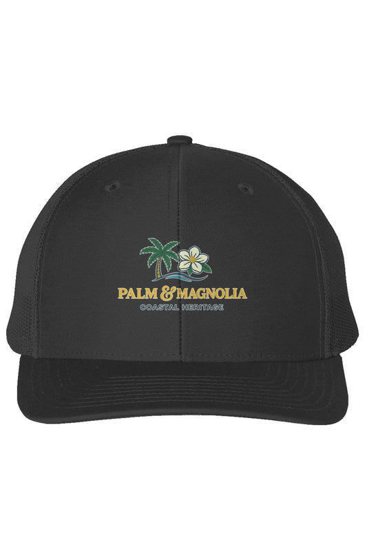 Black snapback trucker cap embroidered with palm tree, magnolia flowers, and "Palm & Magnolia" text.
