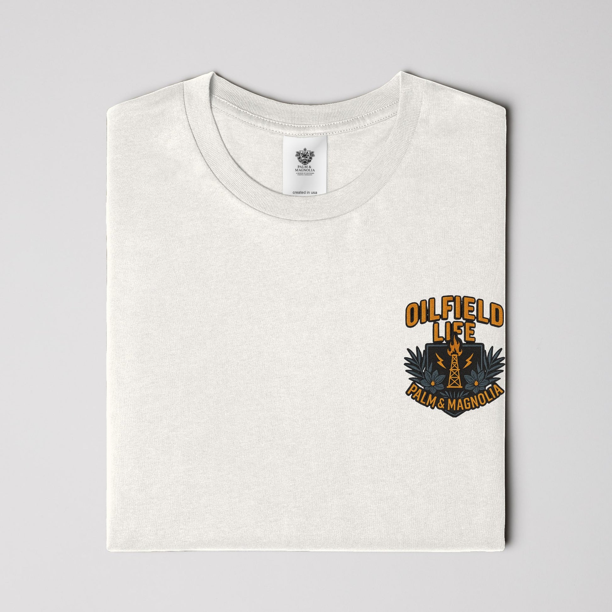 Folded white heavyweight cotton t-shirt with orange "Oilfield Life" and rig emblem on chest.