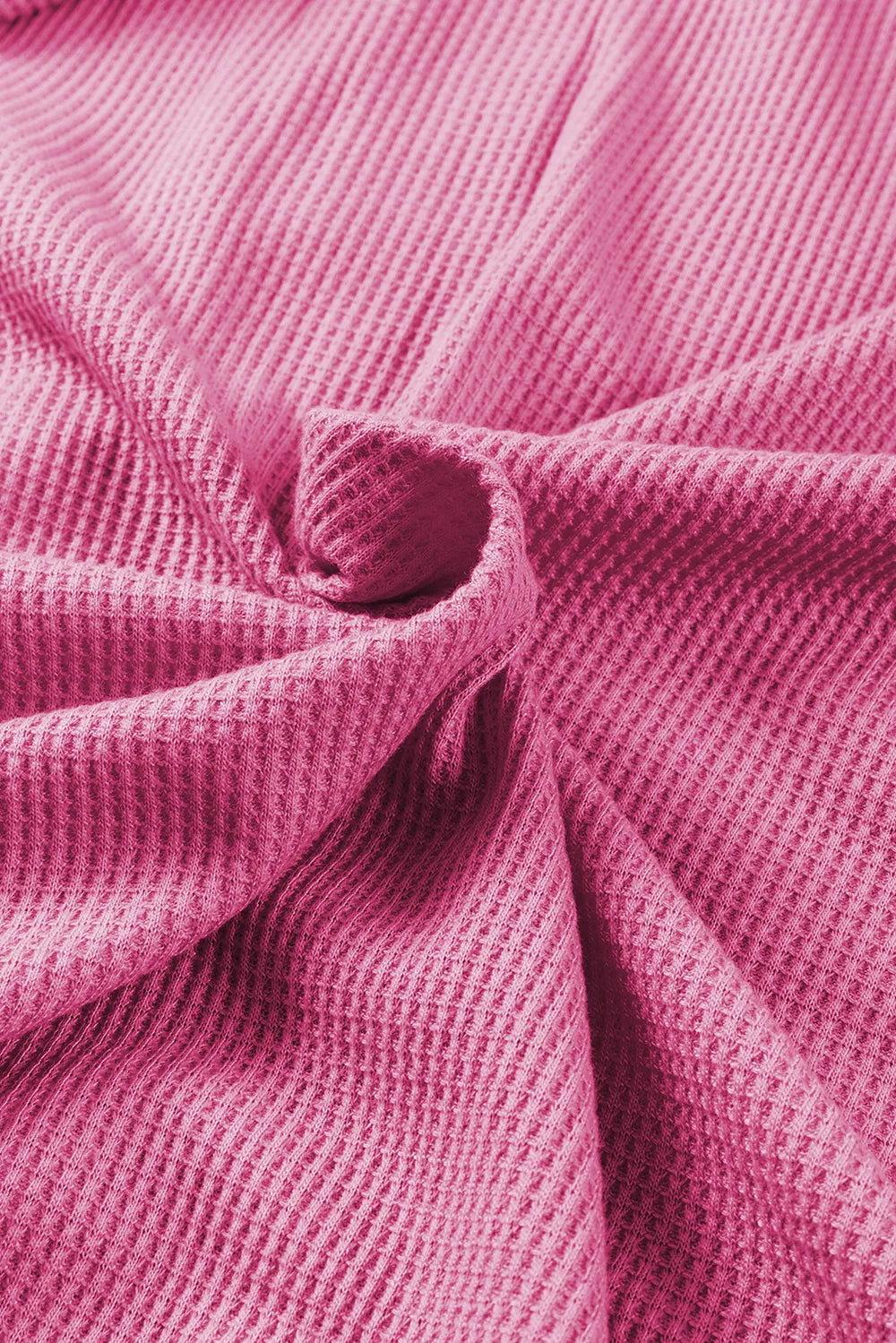 Close-up of soft pink waffle-knit fabric from a zip-up hooded jacket.