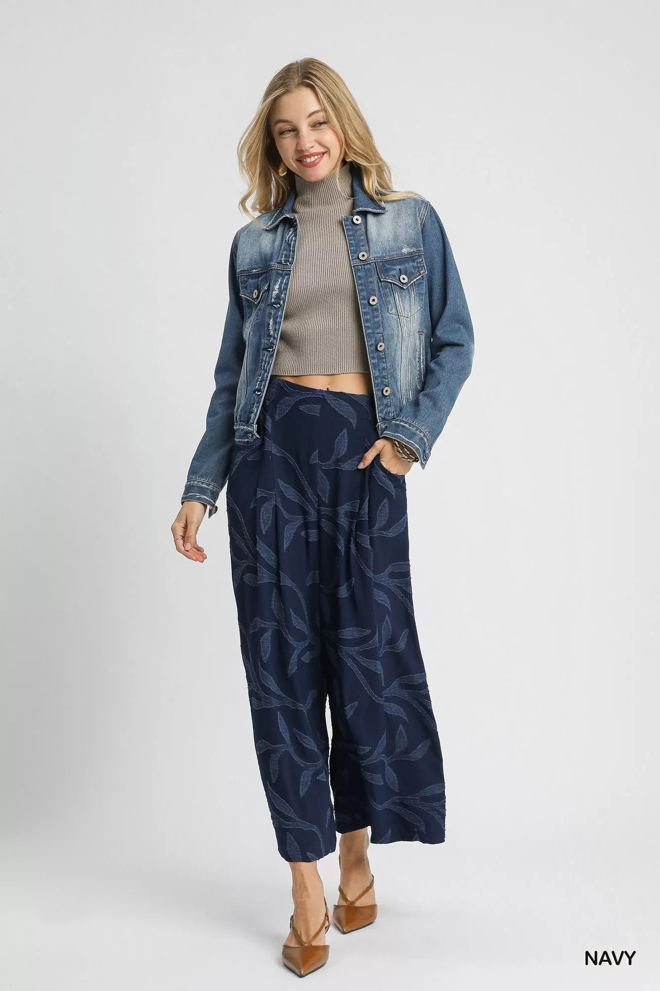 Woman modeling navy jacquard wide-leg pants with pockets, paired with a gray turtleneck and denim jacket.