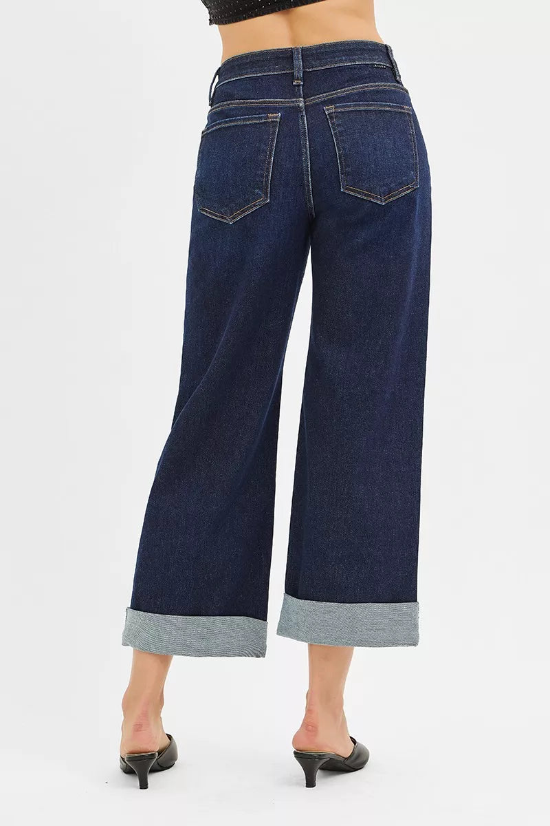 Rear view of mid-rise ankle wide roll-up jeans on a model, showing wide legs and cuffed hems.