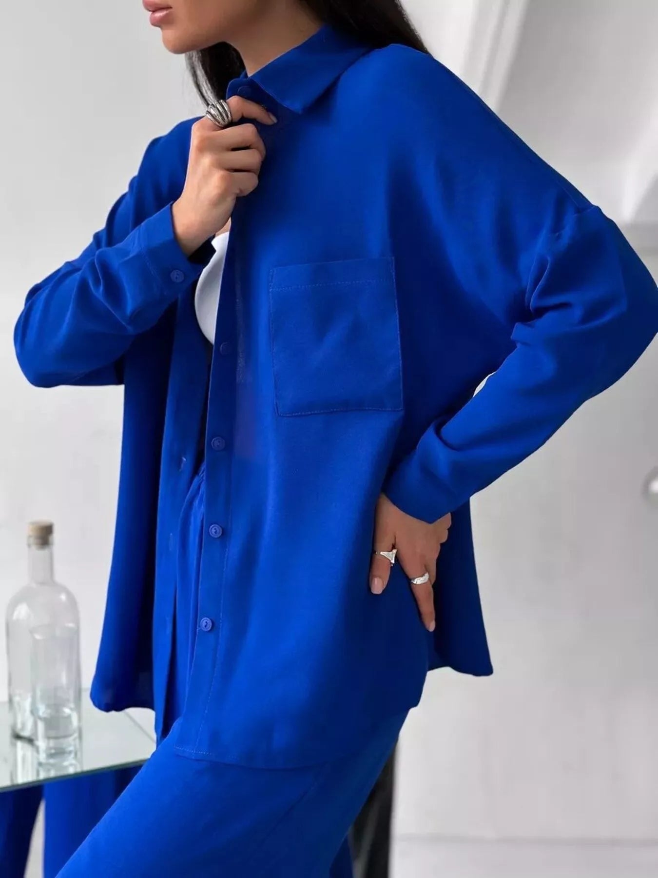 Woman modeling a blue two-piece button-down shirt and pants set with pockets.