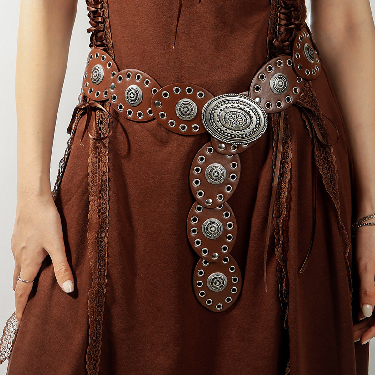 Brown PU leather belt with oval silver buckle and concho details on a model.