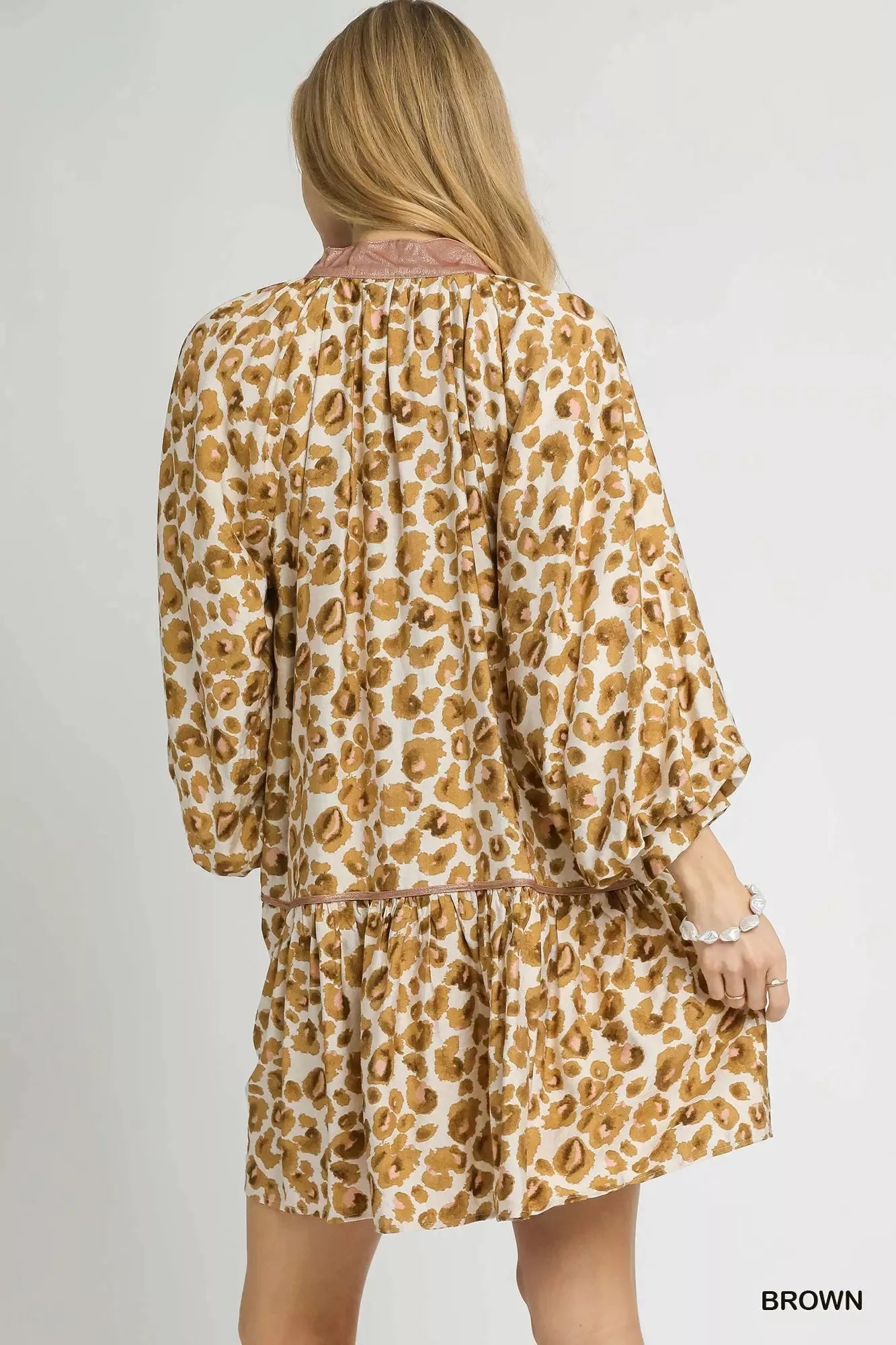 Rear view of a leopard print tiered mini dress with puffed sleeves and ruffled hem.