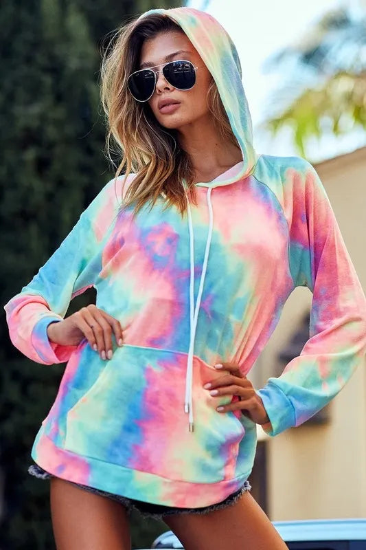 Model poses in vibrant tie-dye French terry hoodie with kangaroo pocket and drawstring hood.
