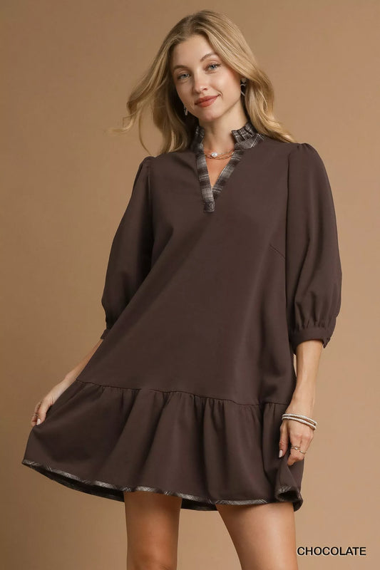 Woman modeling a brown French terry dress with ruffle hem and plaid trim.