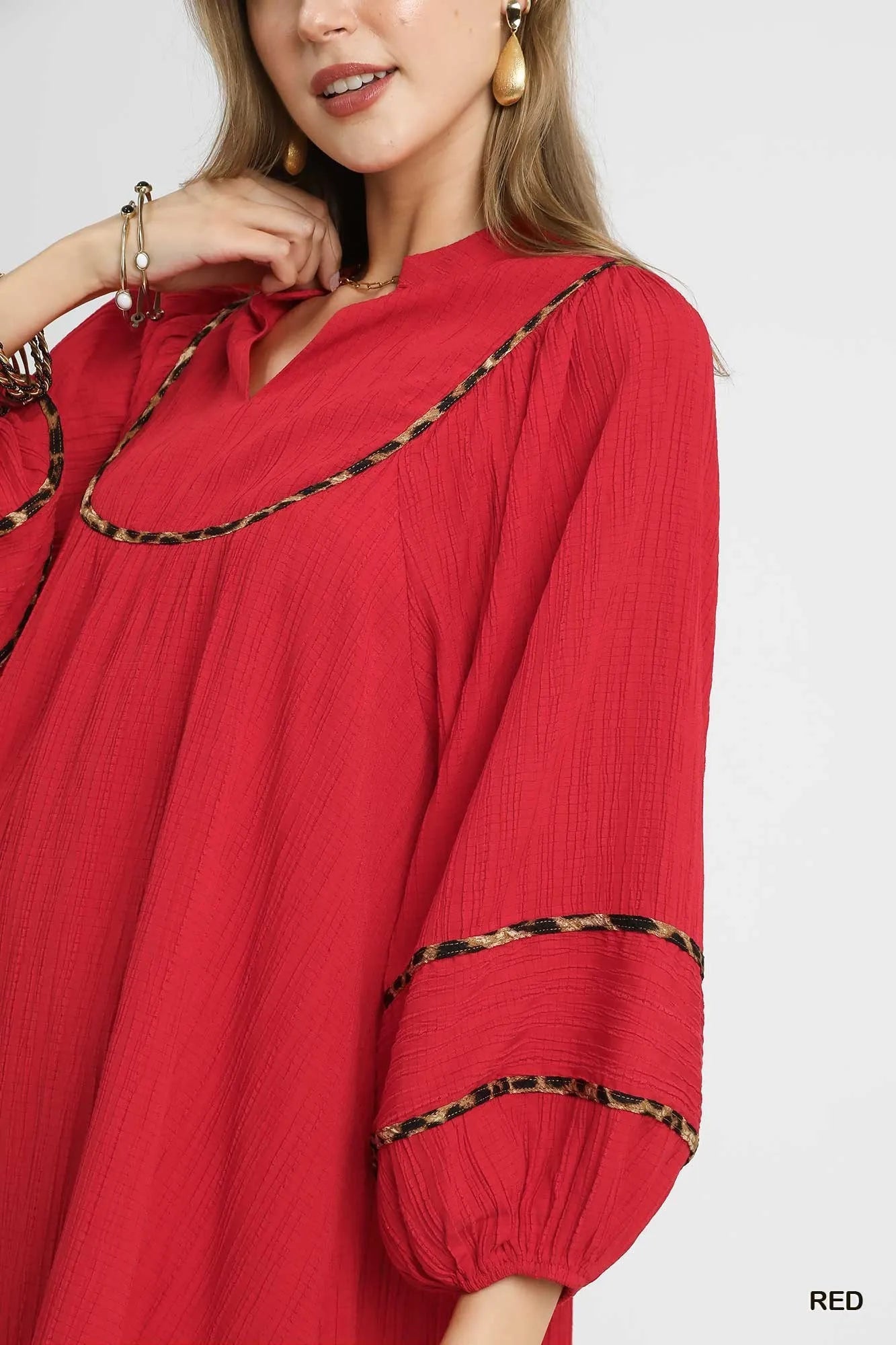 Red textured babydoll dress with black leopard trim on V-neck and sleeves.