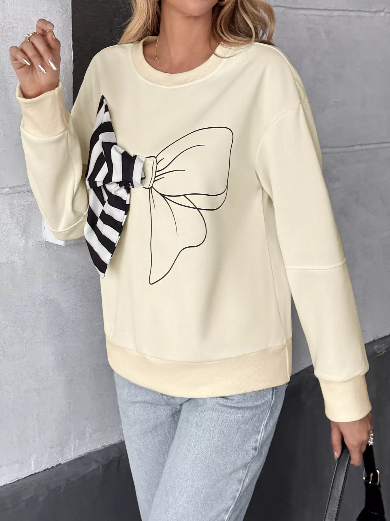 Light gray sweatshirt with a bow, dropped shoulders, and a round neckline.