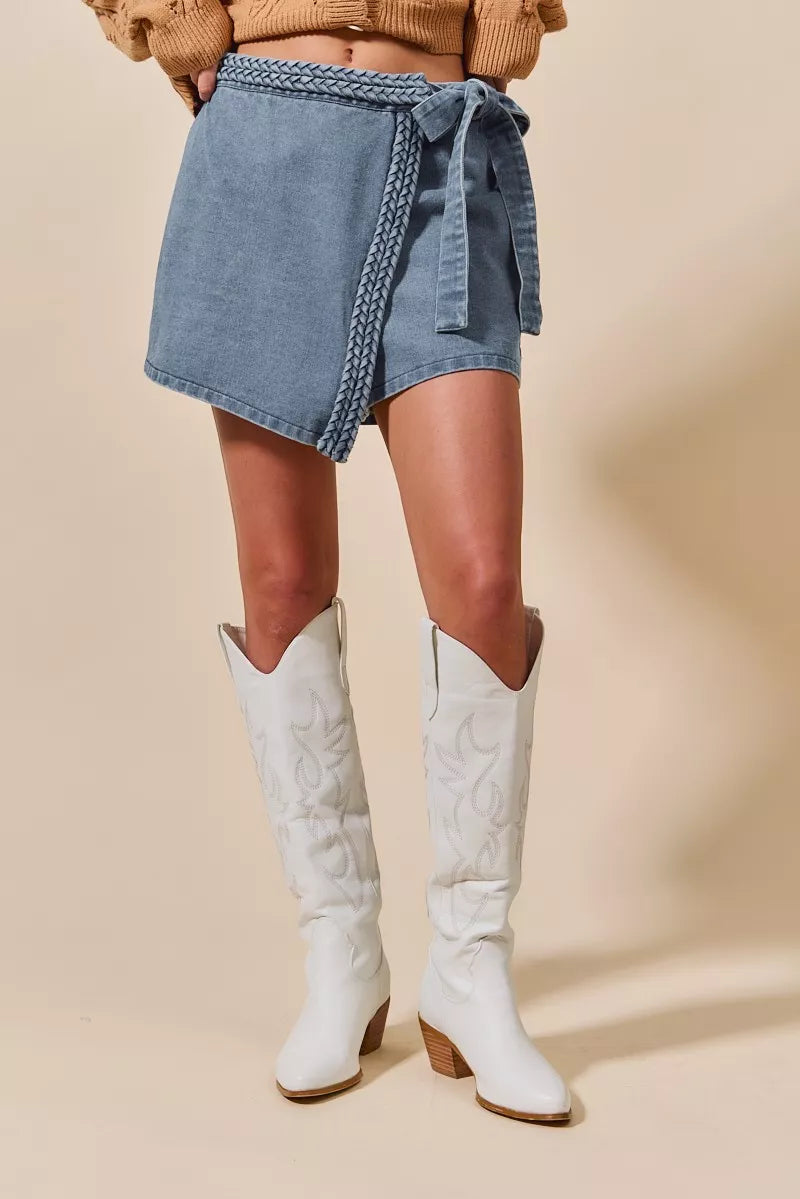 Wrap braided trim denim skort with tie detail and asymmetrical hem.