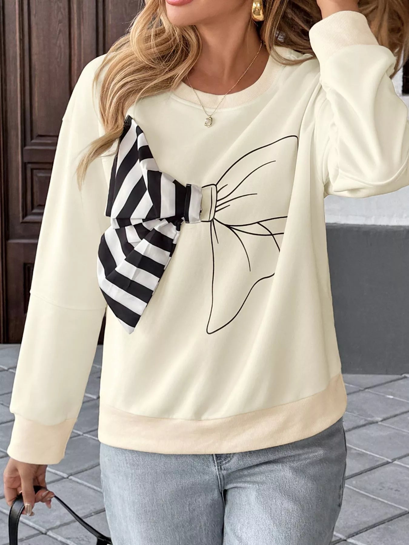 Light pink round neck sweatshirt with dropped shoulders and a bow detail on front