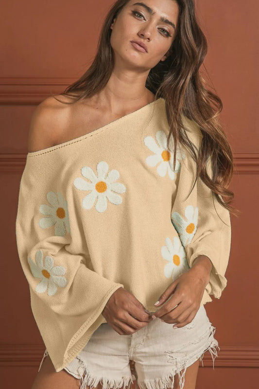 Loose fit knit top with white daisy embroidery, off-shoulder style on model.