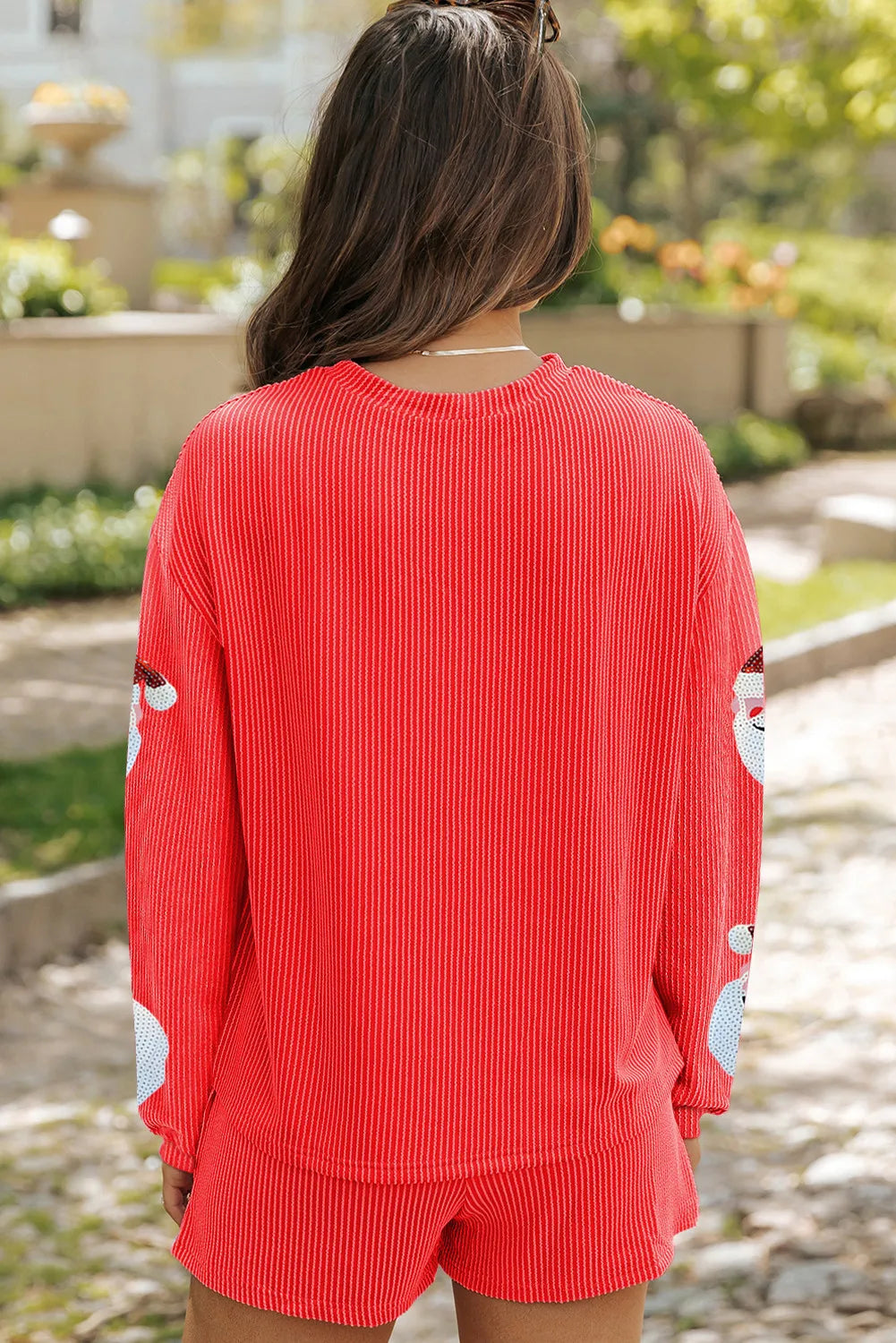 Back view of a red sequin Santa long-sleeve top and shorts set on a model.