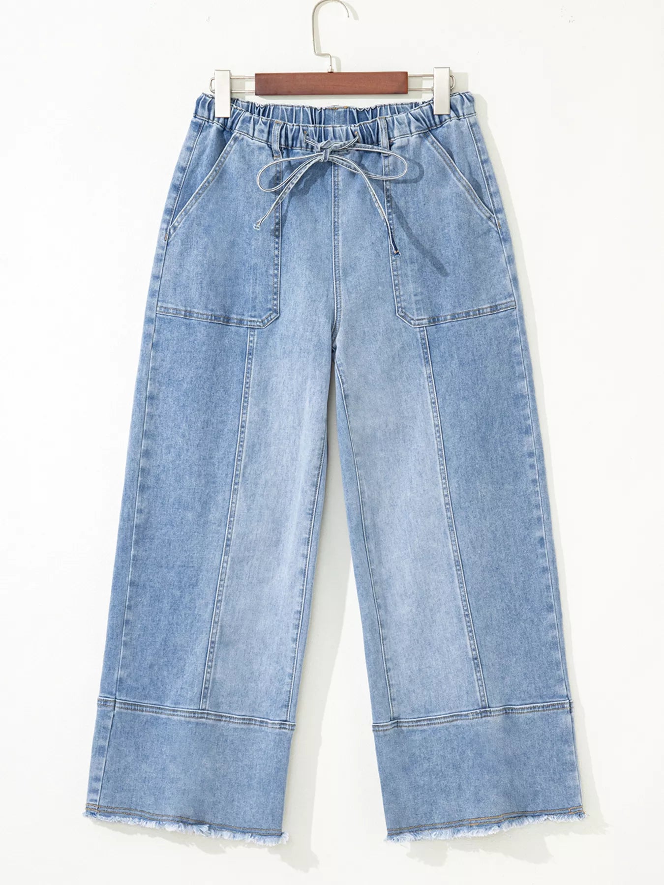 Light wash wide-leg jeans with drawstring waist, pockets, and raw hem.