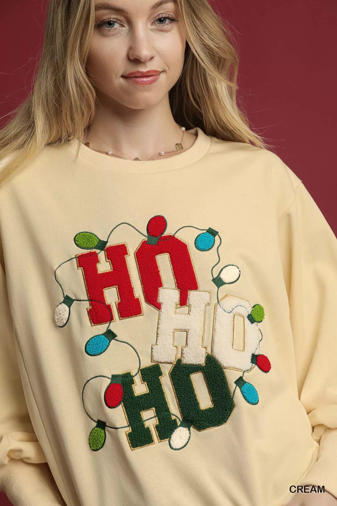 Cream French terry sweatshirt with HO applique and multicolored string lights.