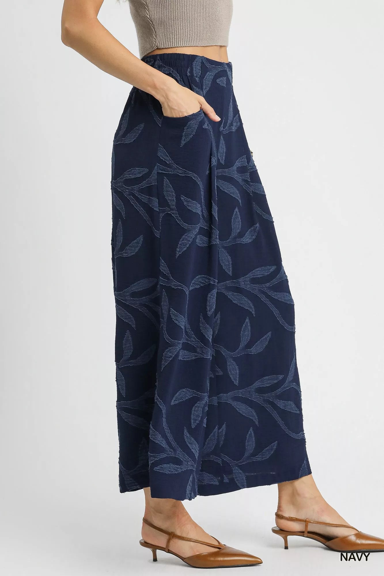 Navy jacquard wide-leg pants with pockets, shown on model with beige top and heels.