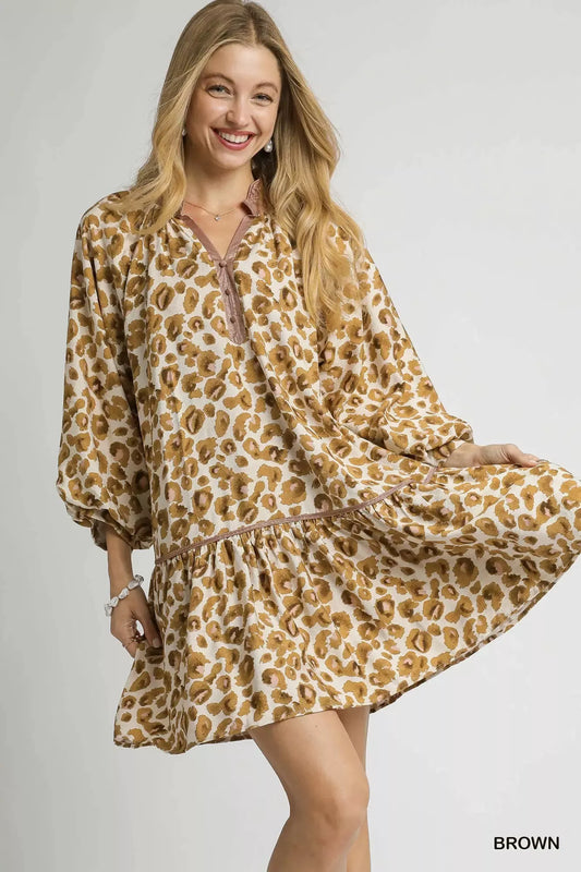 Woman modeling a leopard print tiered mini dress with long sleeves and V-neck.