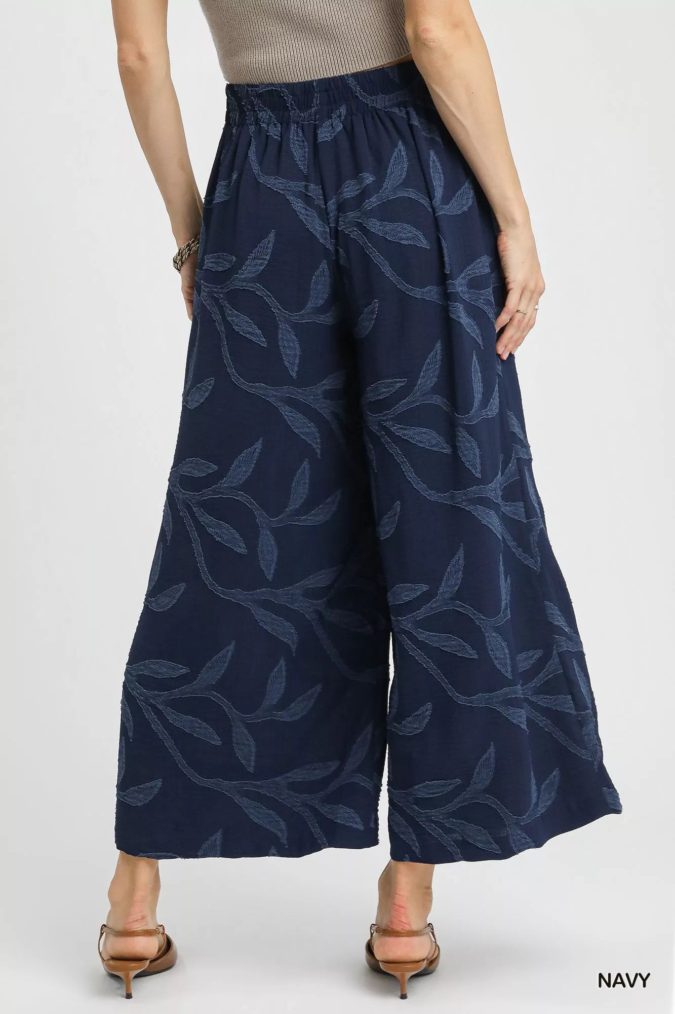 Rear view of navy jacquard wide-leg pants with leaf patterns on a model.