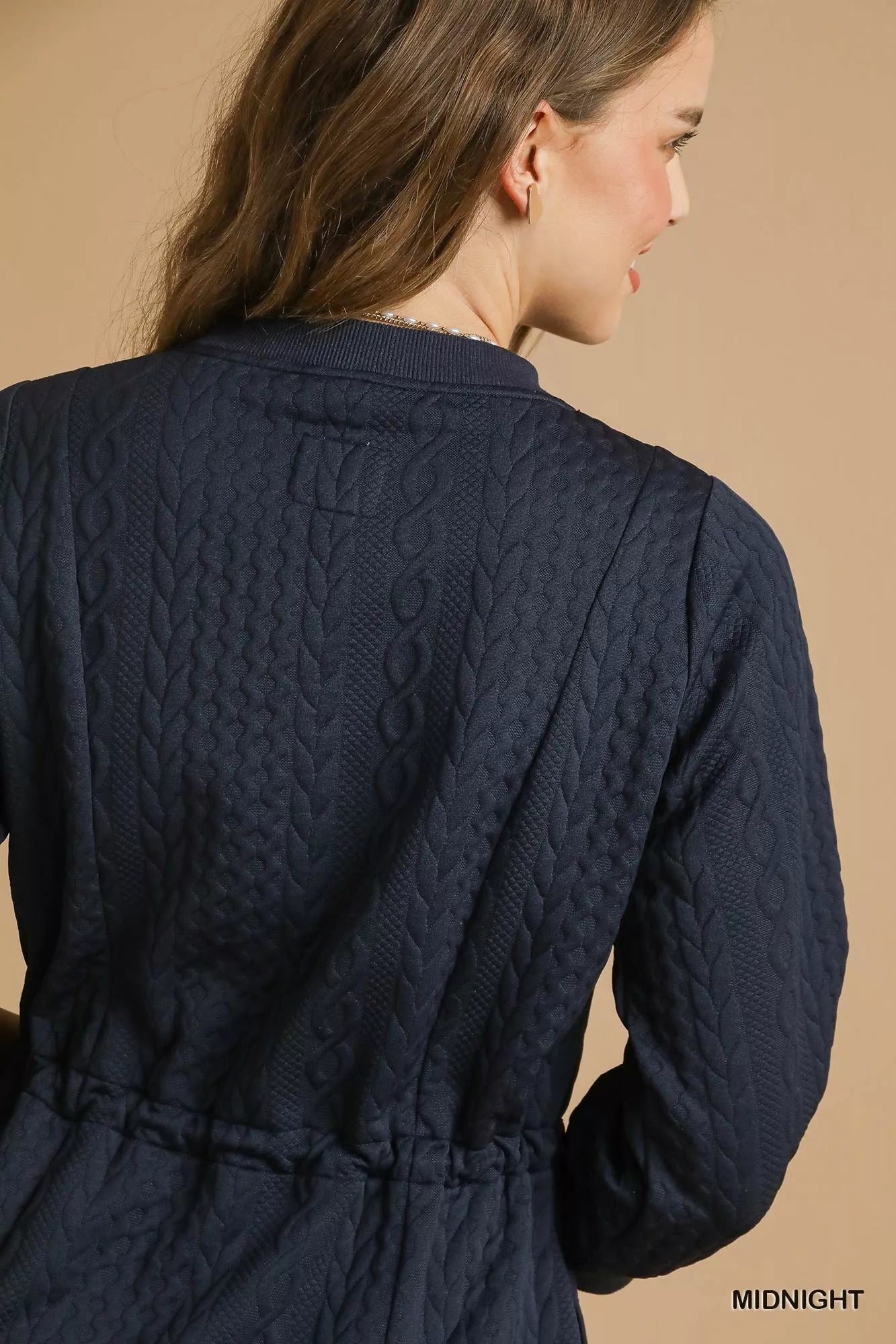 Rear view of navy cable knit mini dress with drawstring waist and pockets.