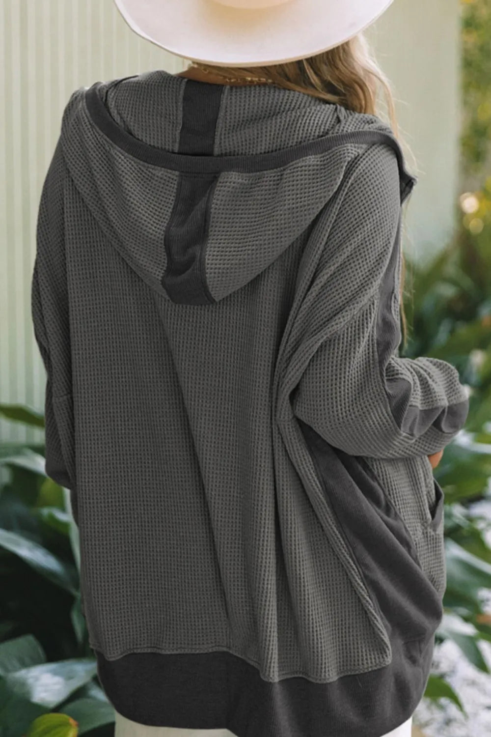Back view of a soft pink waffle-knit zip-up hooded jacket on a model.