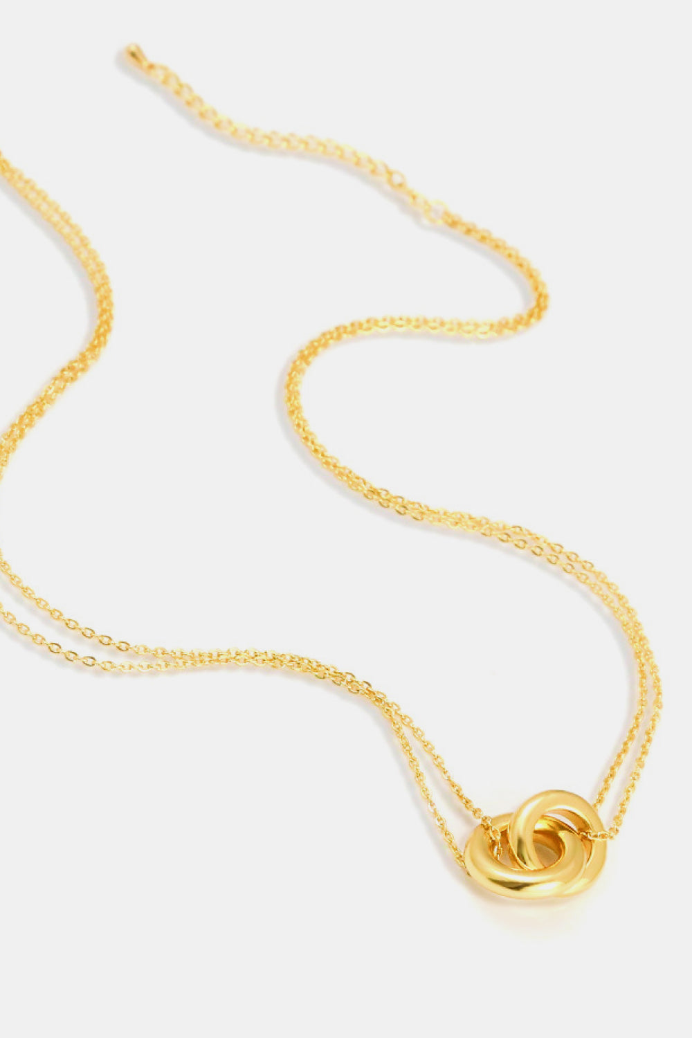 Golden brass necklace with linked ring pendant on a chain.