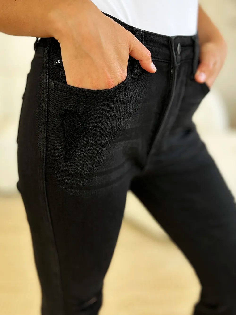 Close-up of a model wearing Judy Blue high-waist black distressed flare jeans.