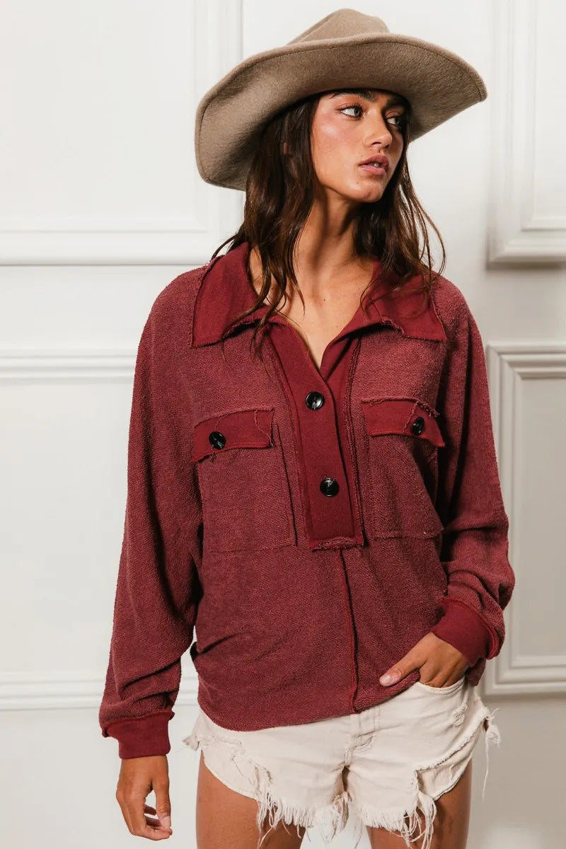 Oversized maroon French terry collared top with buttons and pockets, modeled on a woman.