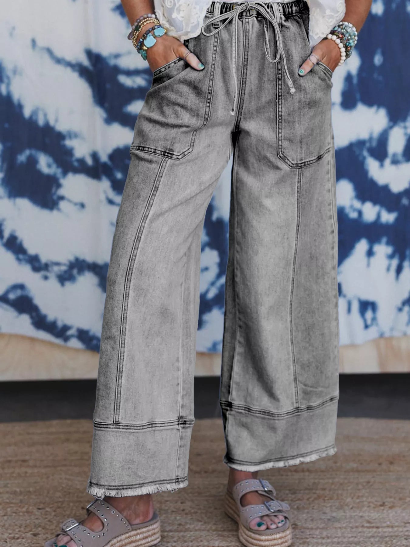 Wide leg light wash jeans with drawstring waist and raw hem, model wearing.