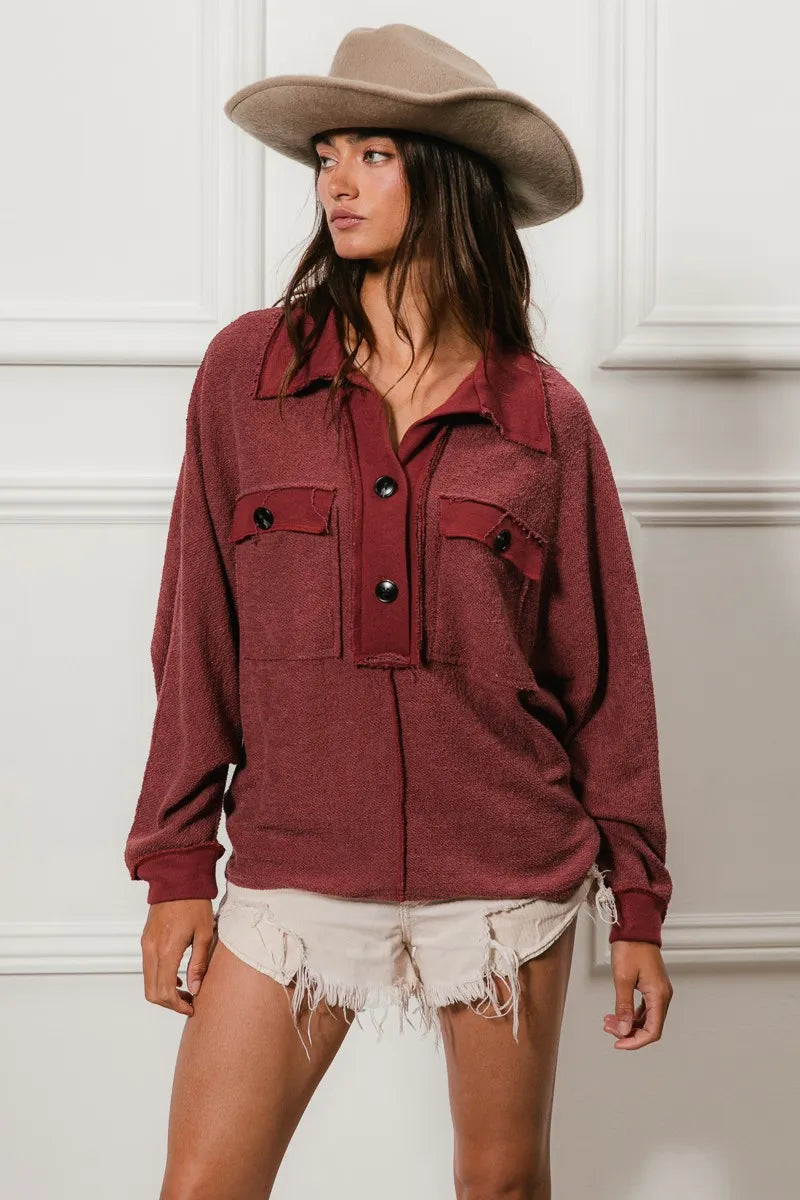 Oversized maroon French terry collared top with buttons and pockets, modeled with a beige cowboy hat and frayed shorts.