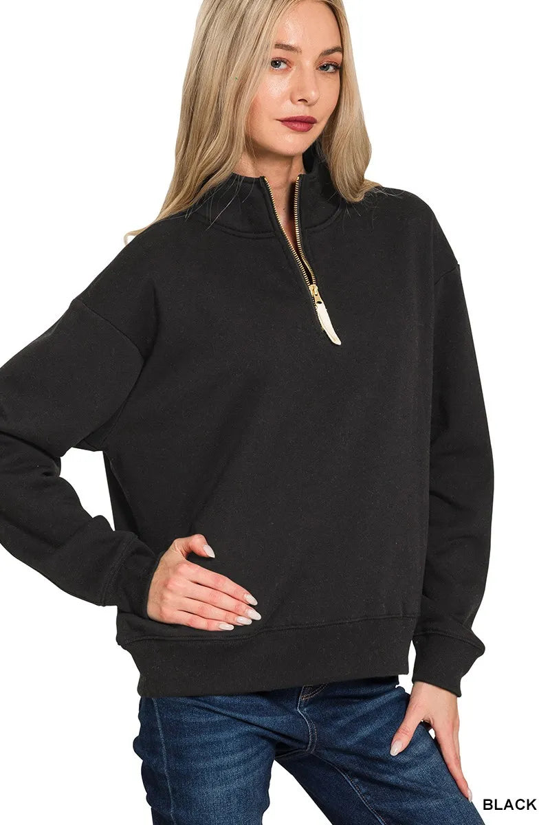 Black oversized fleece half-zip sweatshirt with gold zipper, modeled on a woman.