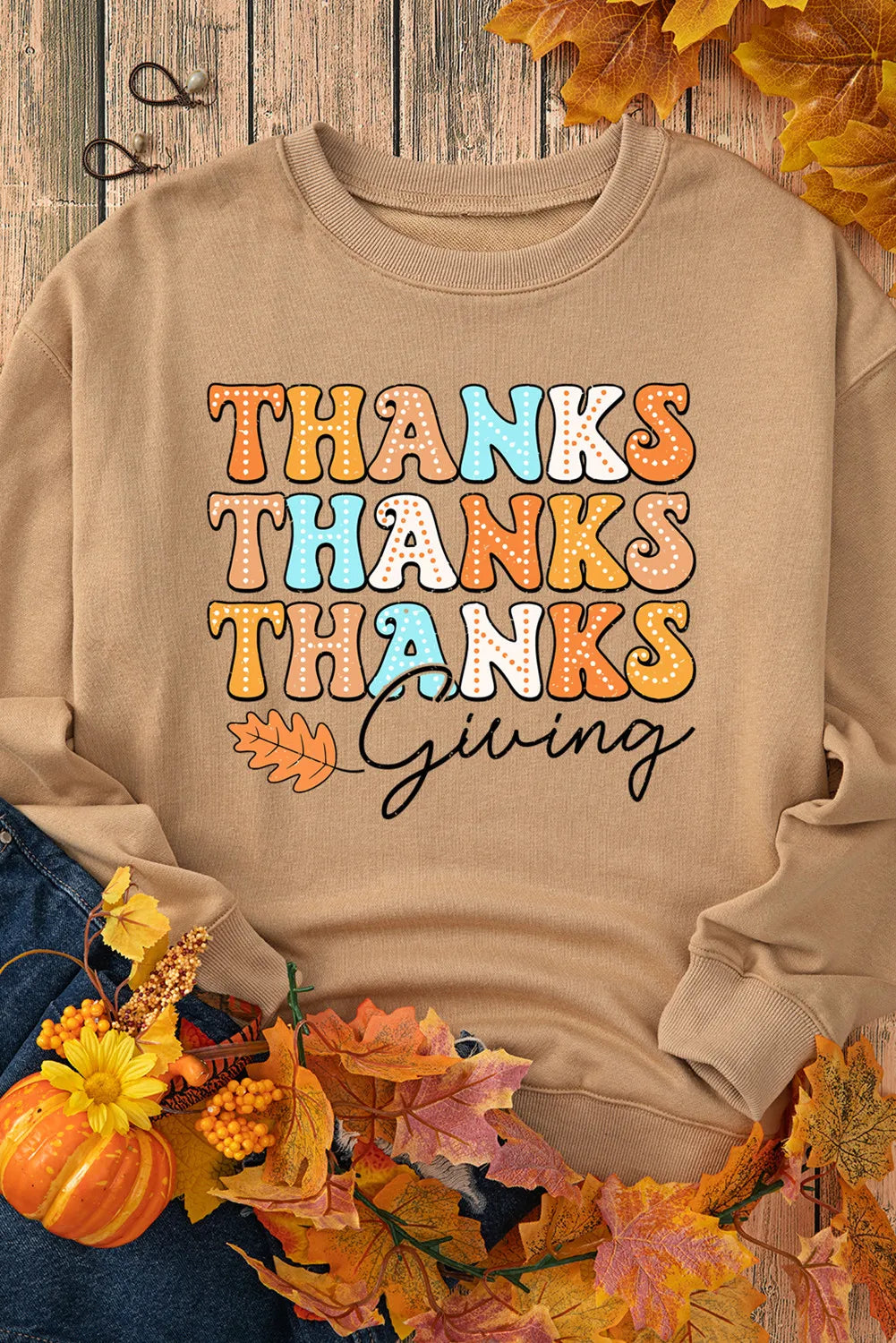 Beige dropped shoulder sweatshirt with colorful "Thanks Giving" text and leaf graphics.