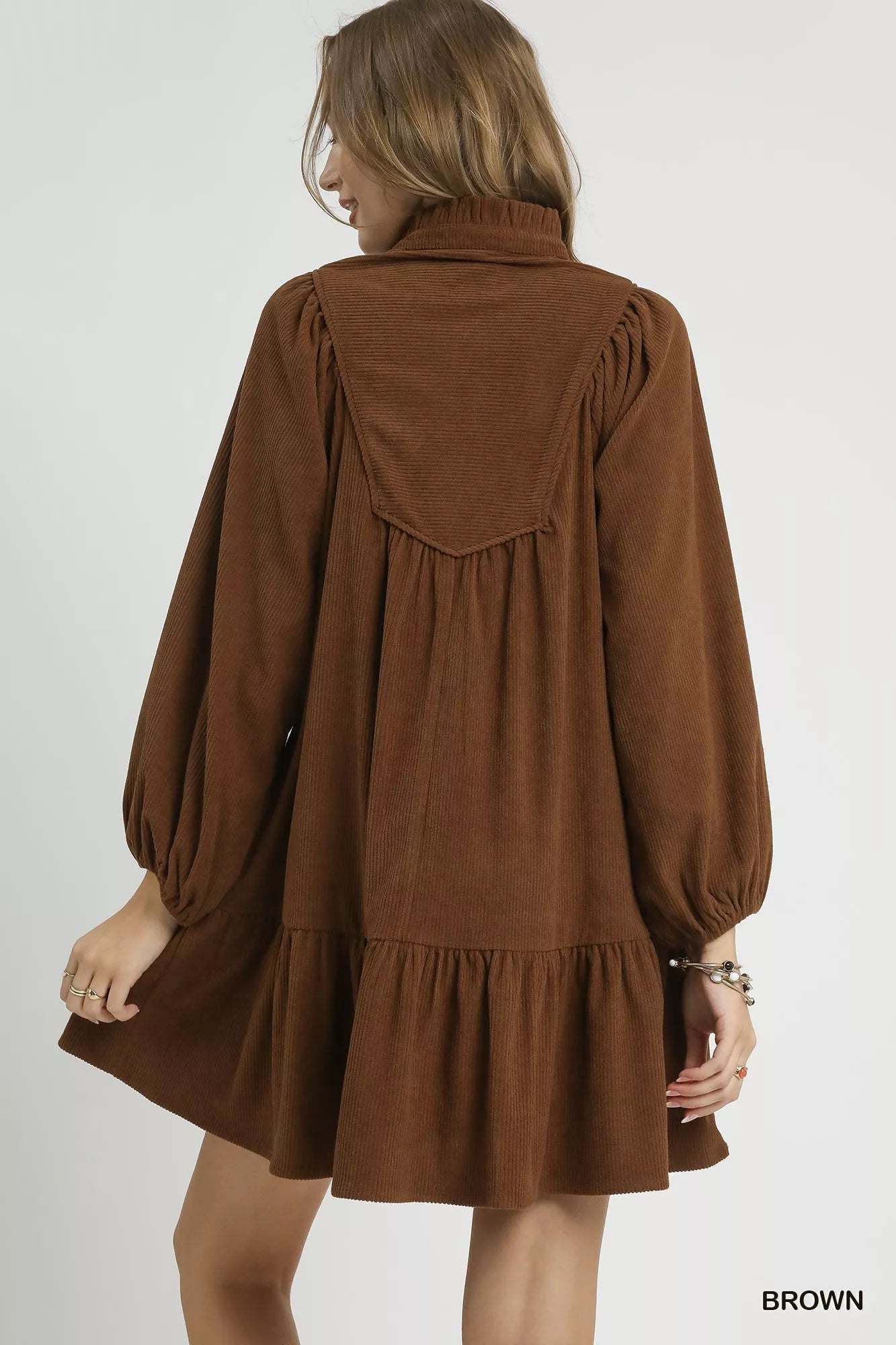 Rear view of brown corduroy tiered babydoll dress with ruffled hem.