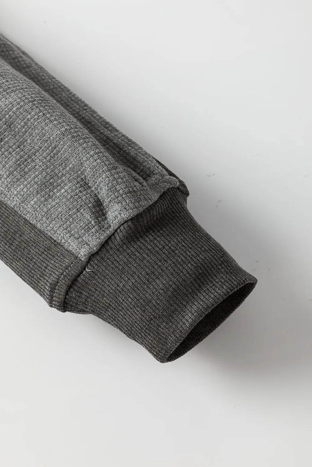 Close-up of soft pink waffle-knit sleeve and cuff on a zip-up hooded jacket.