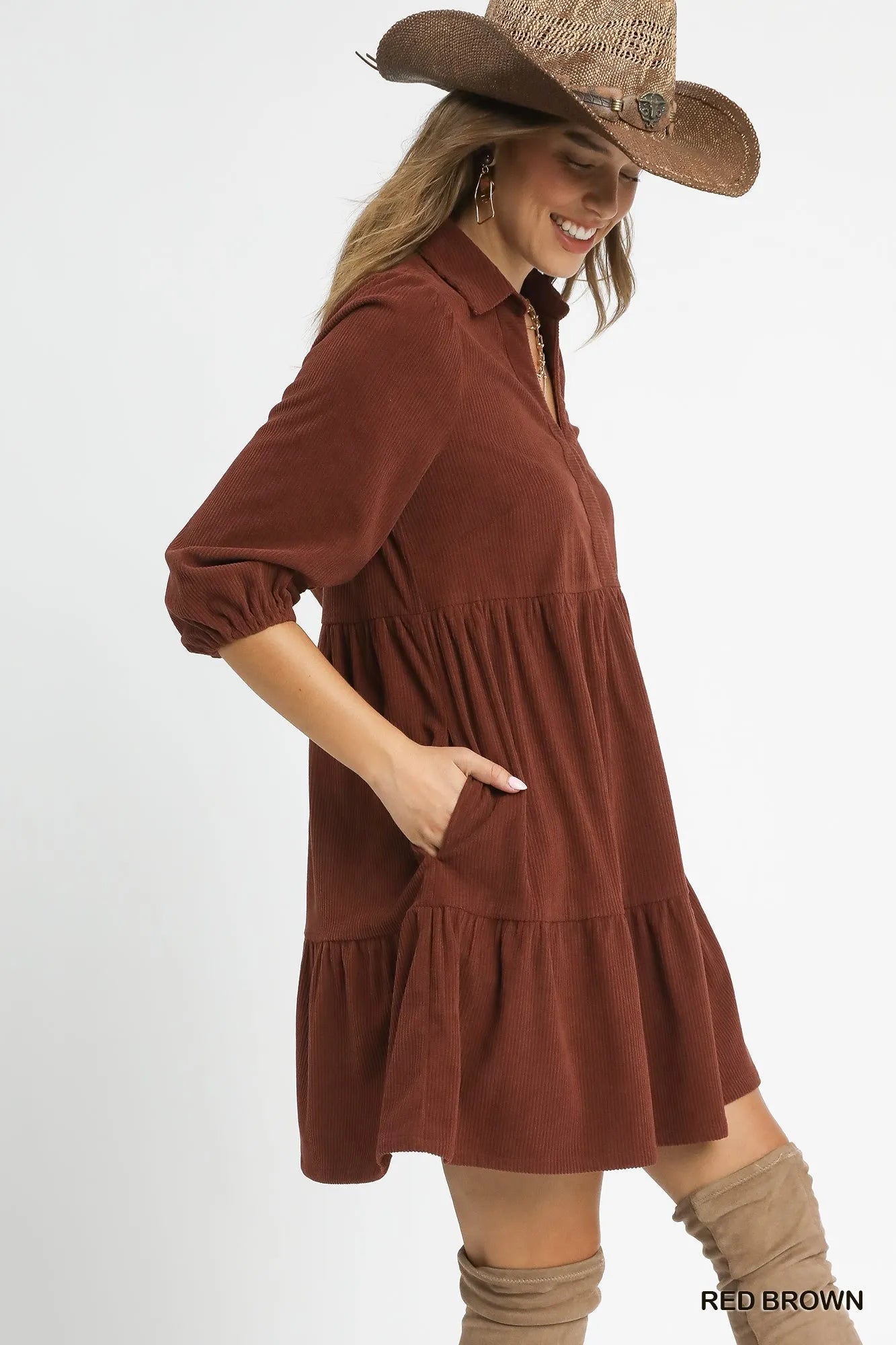 Woman modeling a rust-colored tiered corduroy mini dress with balloon sleeves and a cowboy hat.