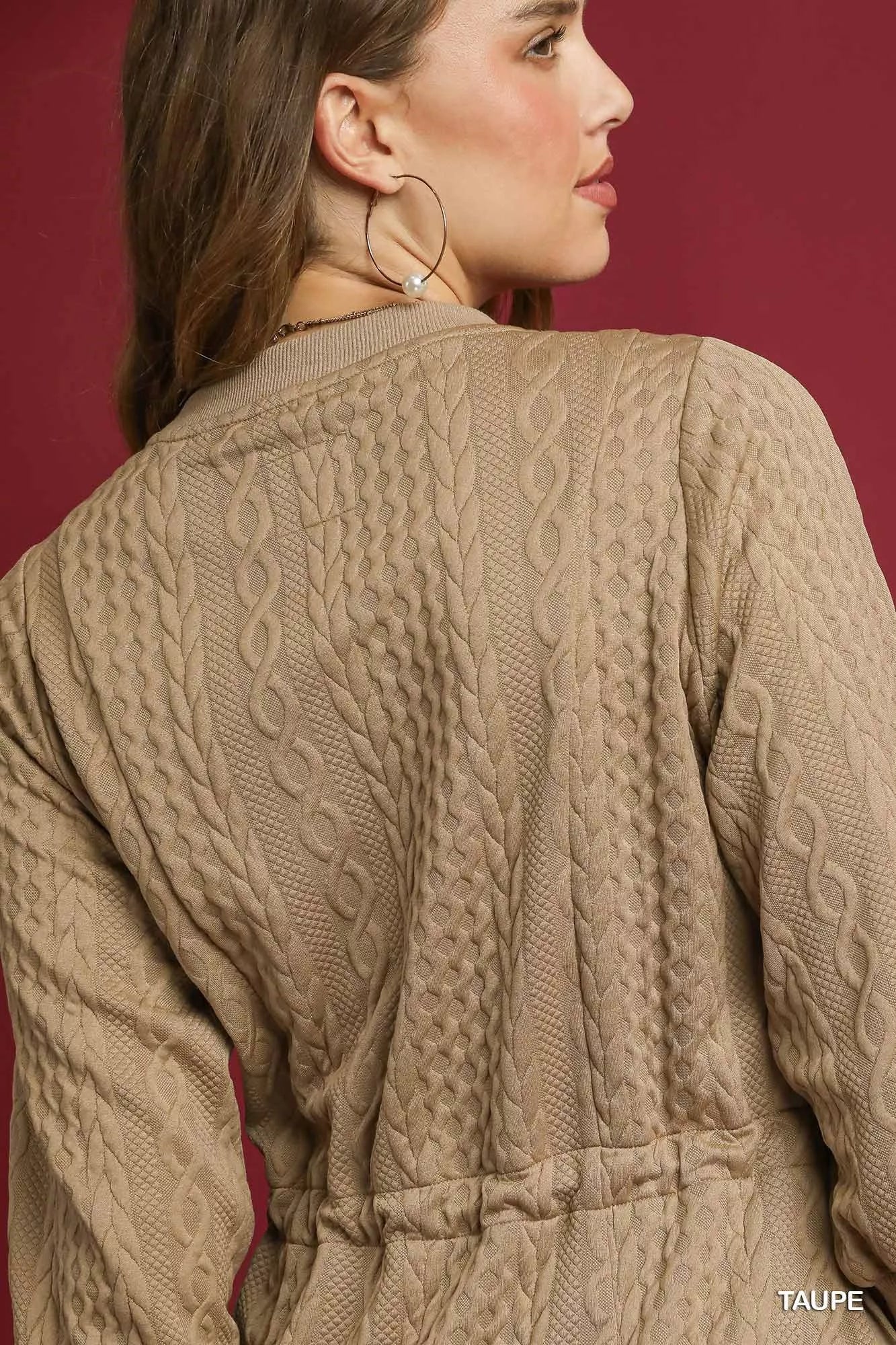 Side view of a woman modeling a beige cable knit mini dress with drawstring waist and pockets.