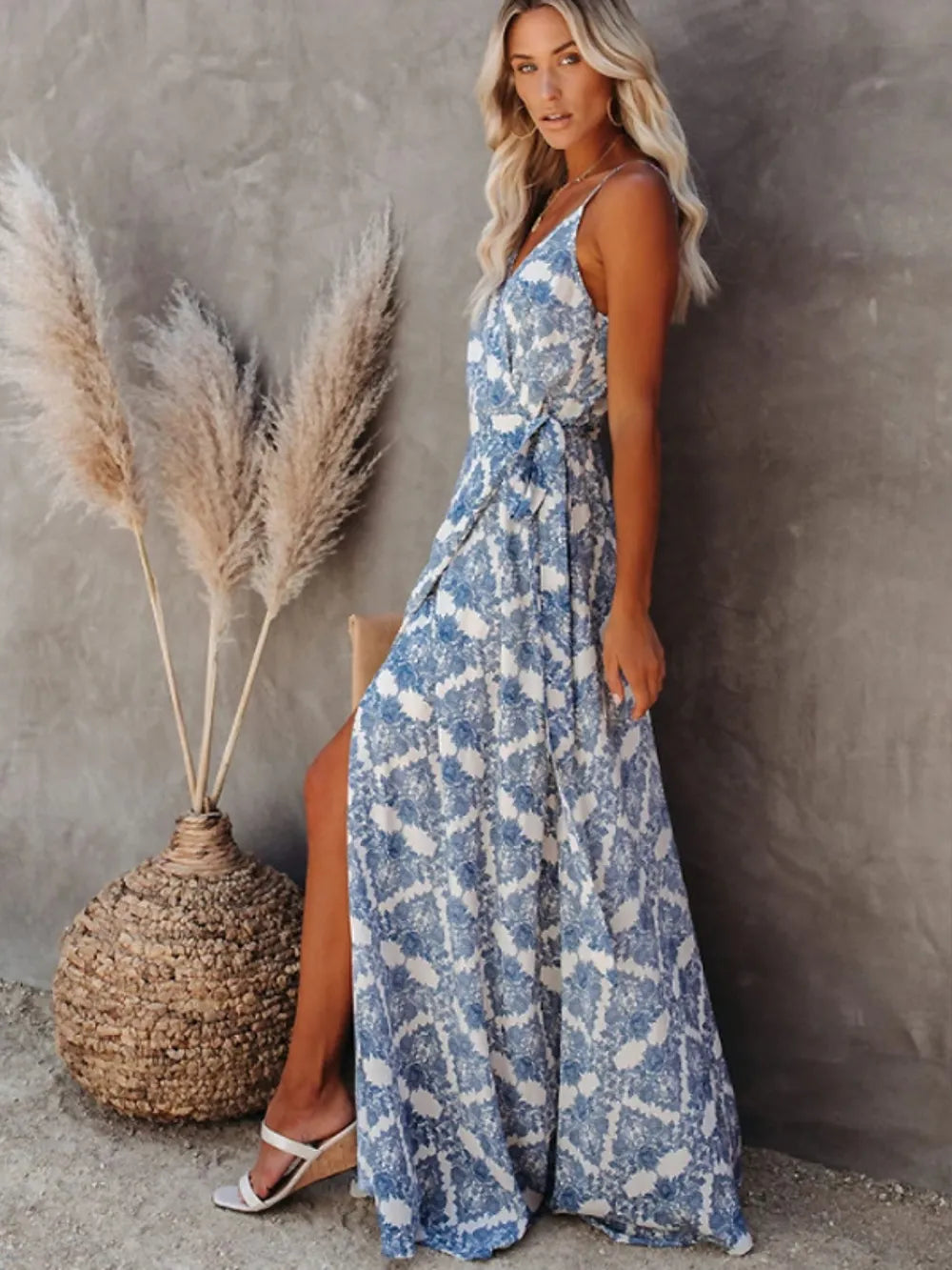 Blue ikat printed tied maxi cami dress on a model with blonde hair, standing by pampas grass.