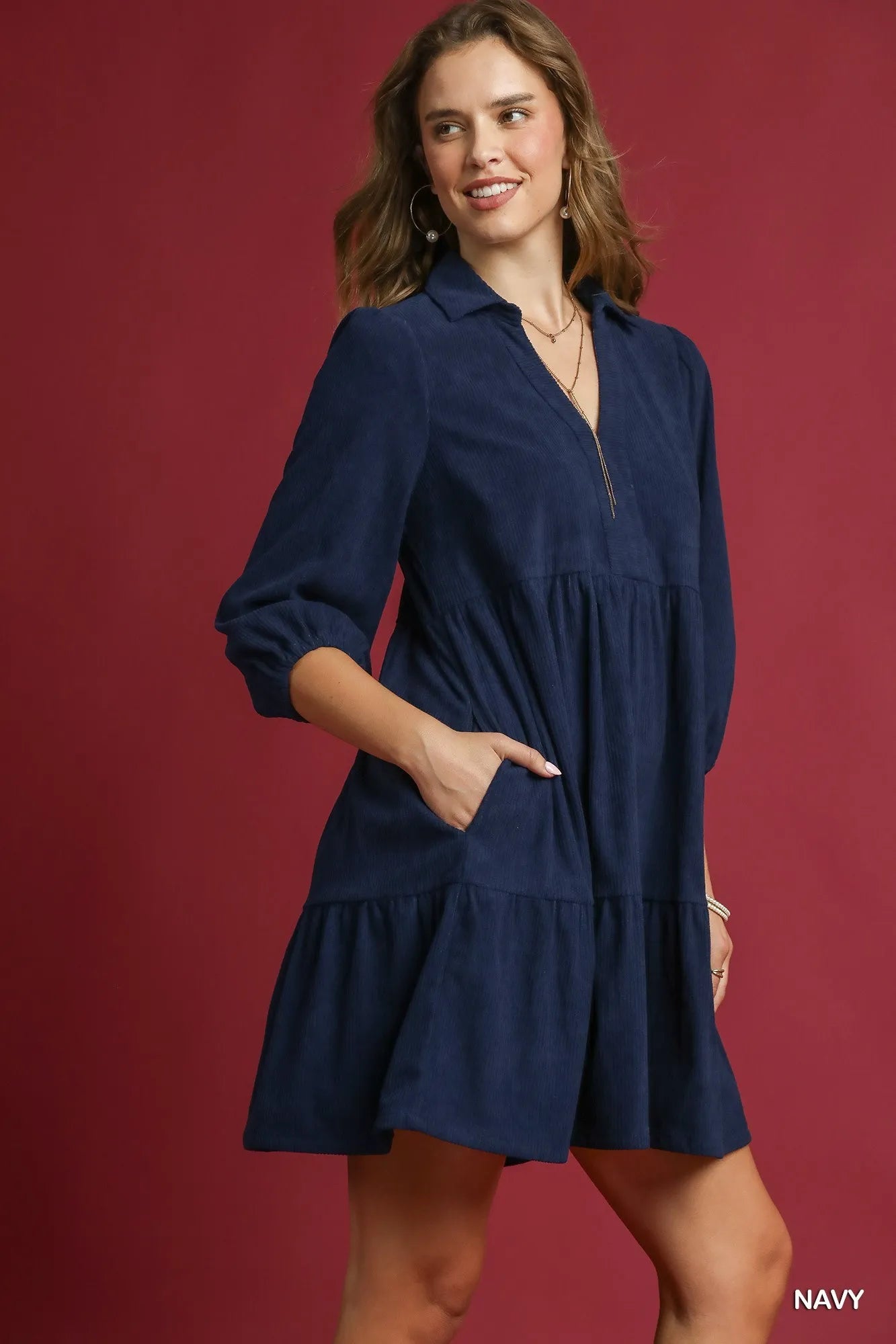 Navy tiered corduroy mini dress with balloon sleeves and pockets, modeled on a woman.