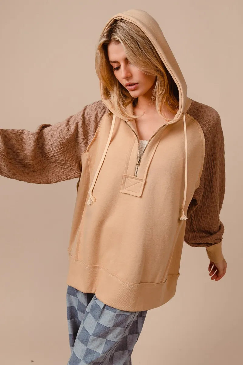 Beige half-zip French terry hoodie with knit sleeves, modeled on a woman.