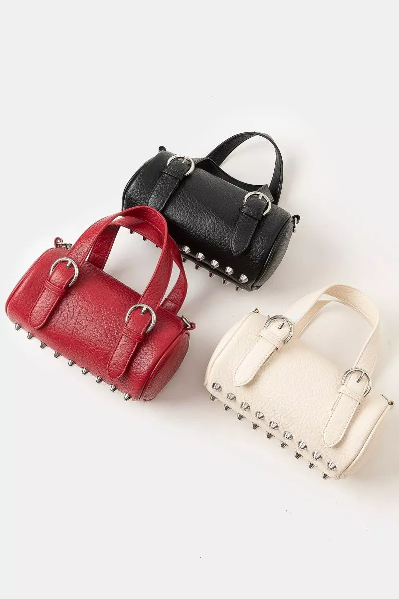Burgundy faux leather mini cylinder bag with buckle straps and stud details.