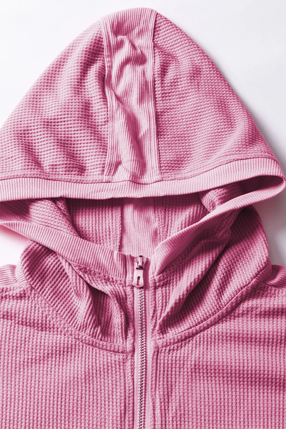 Pink waffle-knit zip-up hooded jacket with front pockets.
