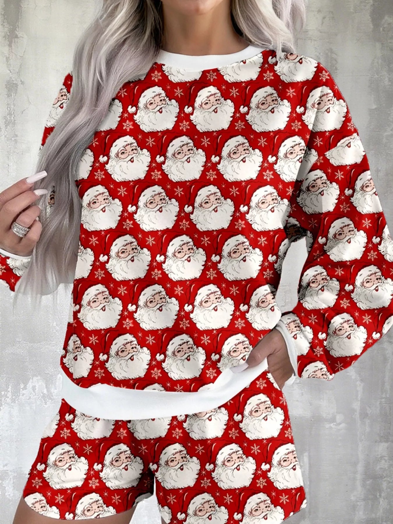 Woman modeling pink two-piece lounge set with festive Santa print.