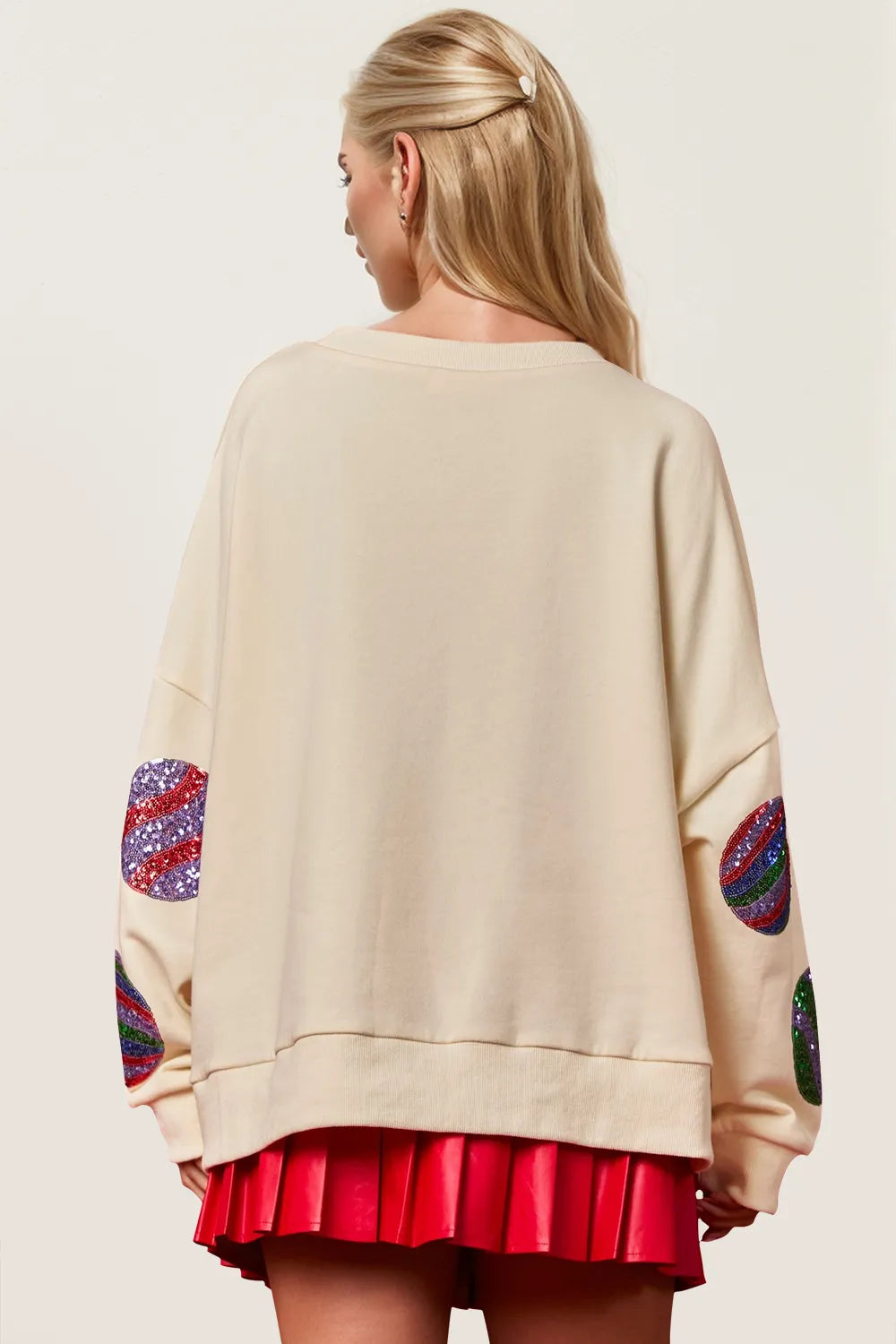 Rear view of a cream long-sleeve sweatshirt with colorful sequin patches on elbows.