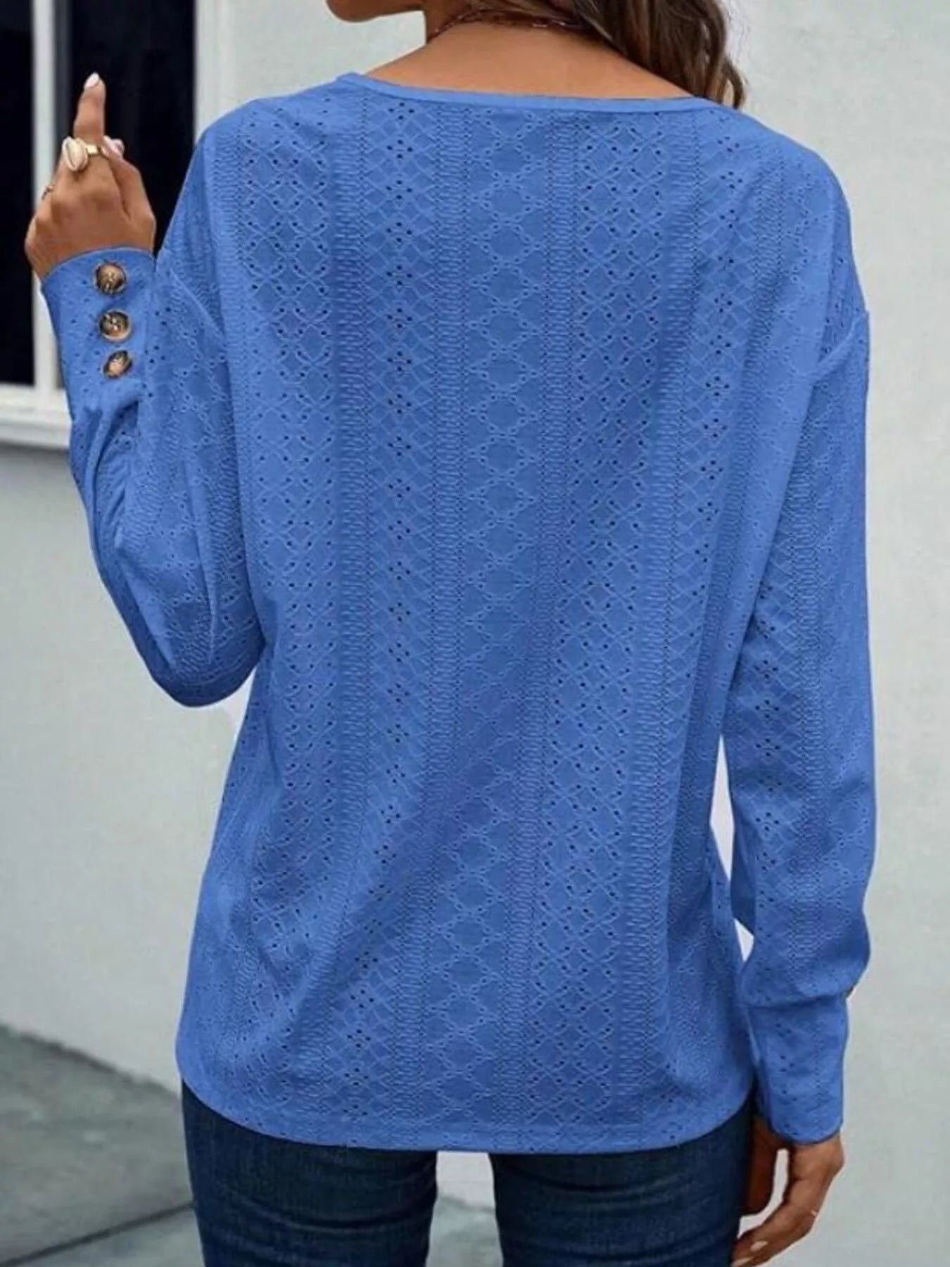 Long sleeve eyelet v-neck blouse in a polyester blend with decorative buttons.