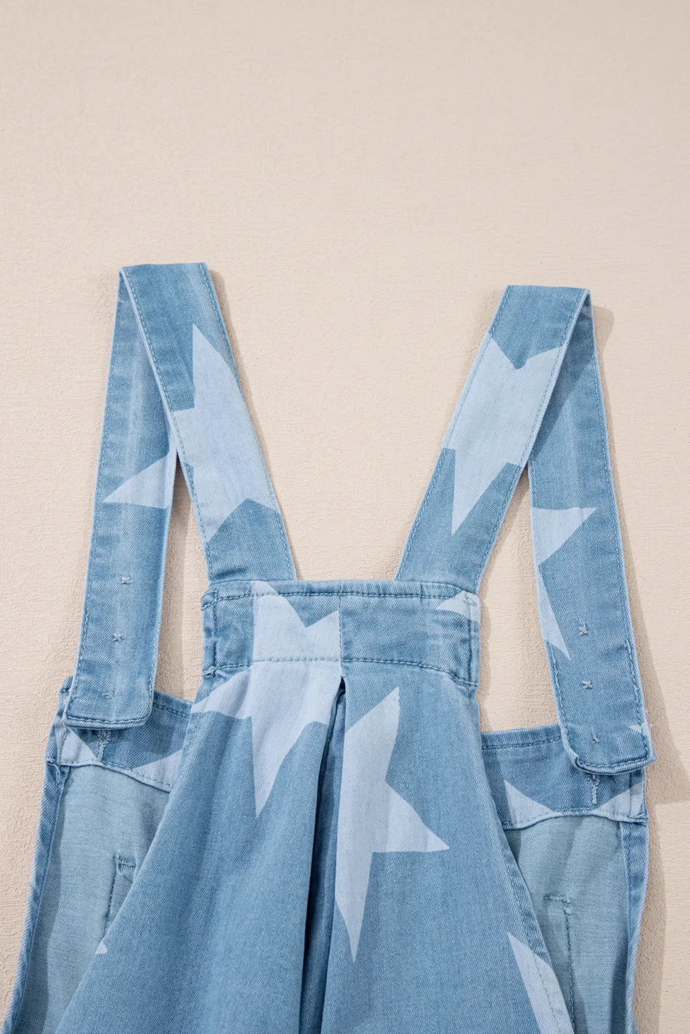 Star print denim overalls with a square neck and pocketed design in a cotton blend.