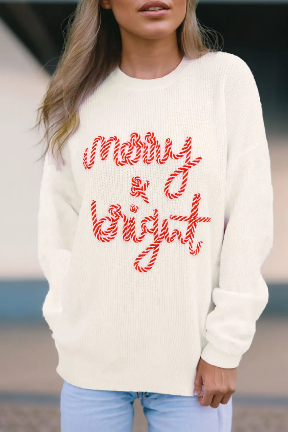 Cream round neck sweater with red "Merry & Bright" text, model in front.