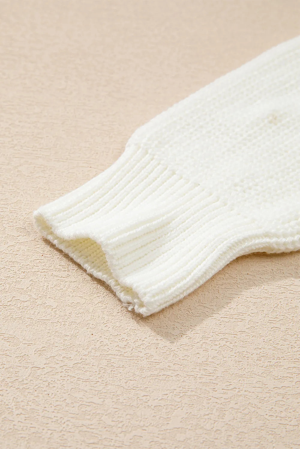 Cream acrylic cotton round neck sweater with ribbed cuffs on a neutral background.