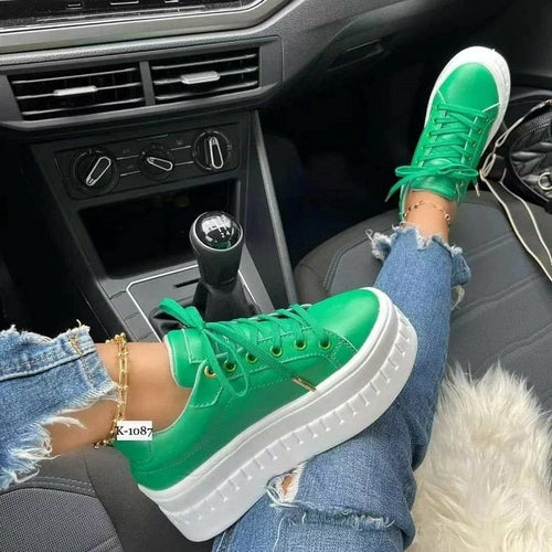 Woman's tan leather platform sneakers with laces, on foot in car.