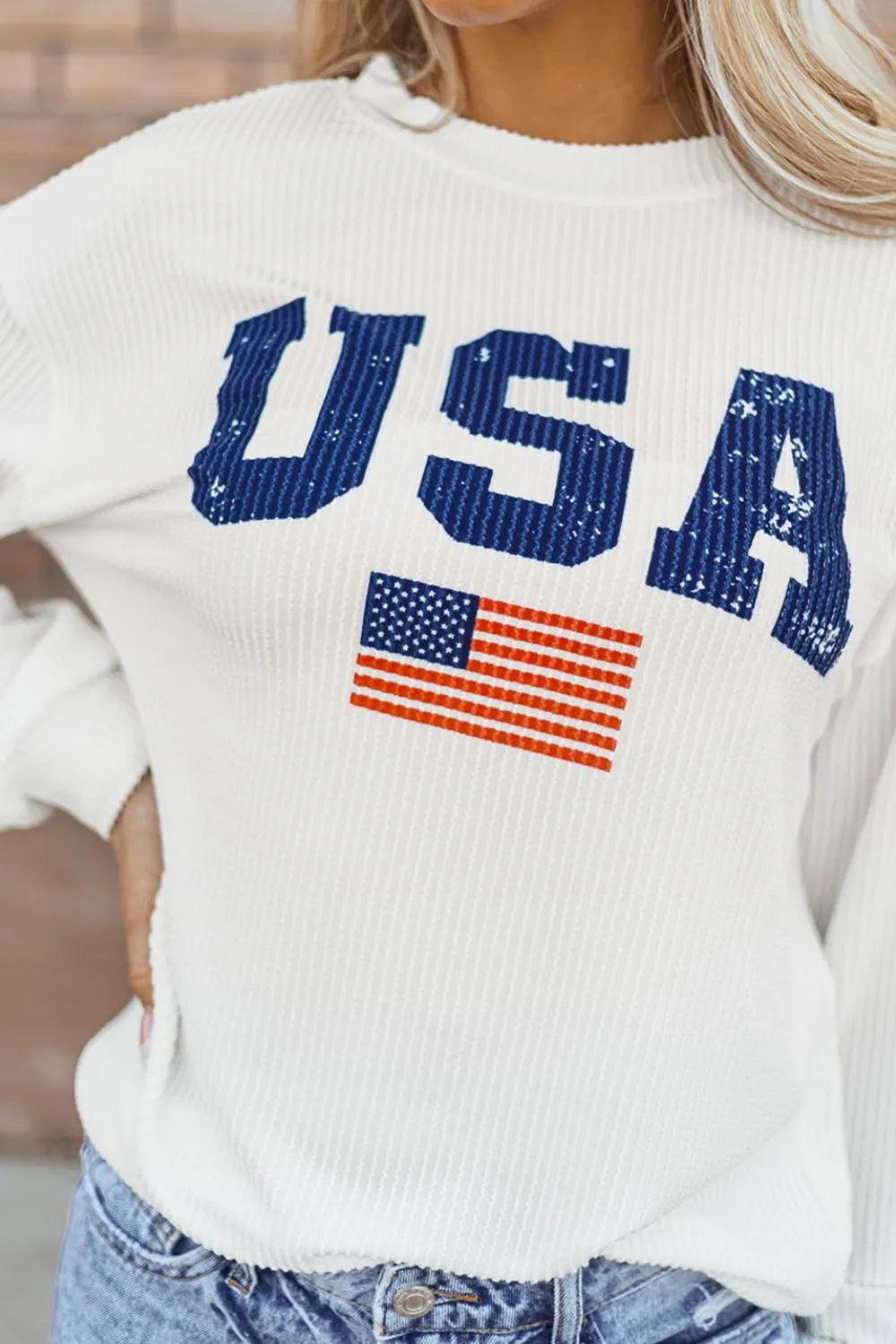 A corded long sleeve sweatshirt featuring the US flag design in a polyester blend.