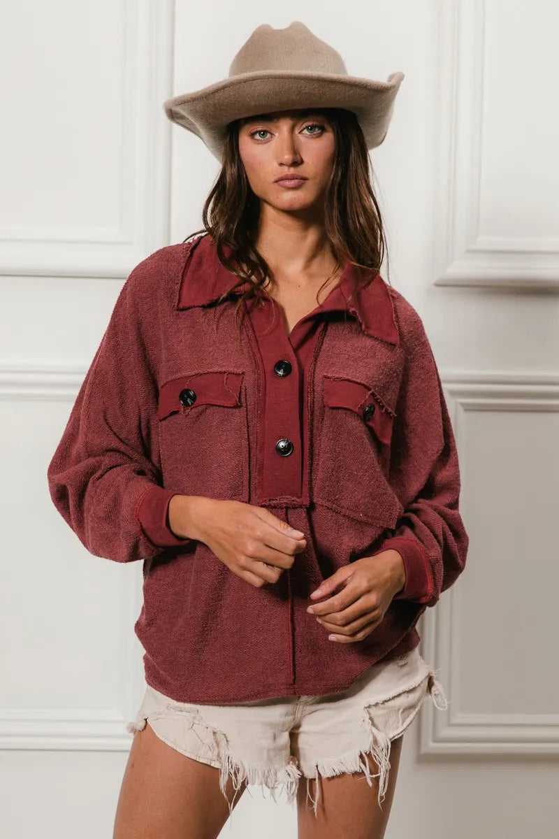 Oversized maroon French terry collared top with buttons and pockets, modeled on a woman.